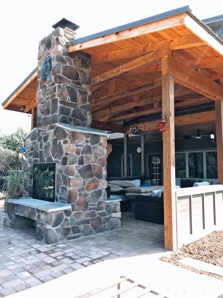 There is a stone fireplace in the backyard of a house.