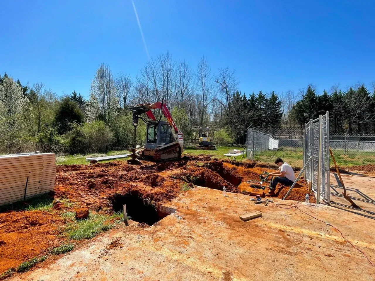 A man is sitting on the ground in front of a construction site.