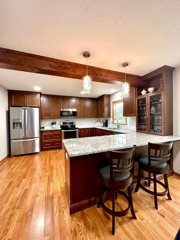 A kitchen with wooden cabinets , granite counter tops , stainless steel appliances and a large island.