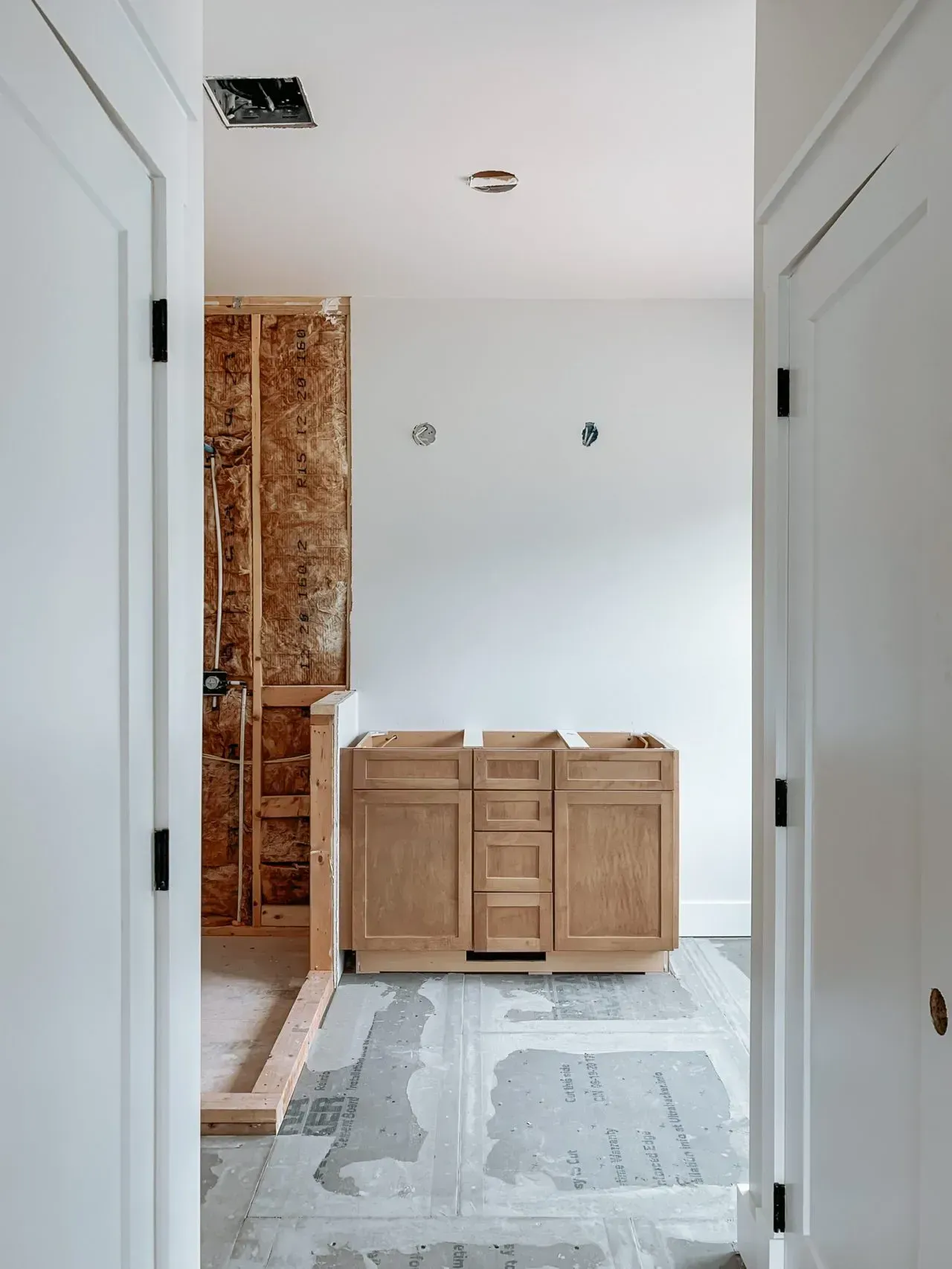 A hallway leading to a bathroom with wooden cabinets