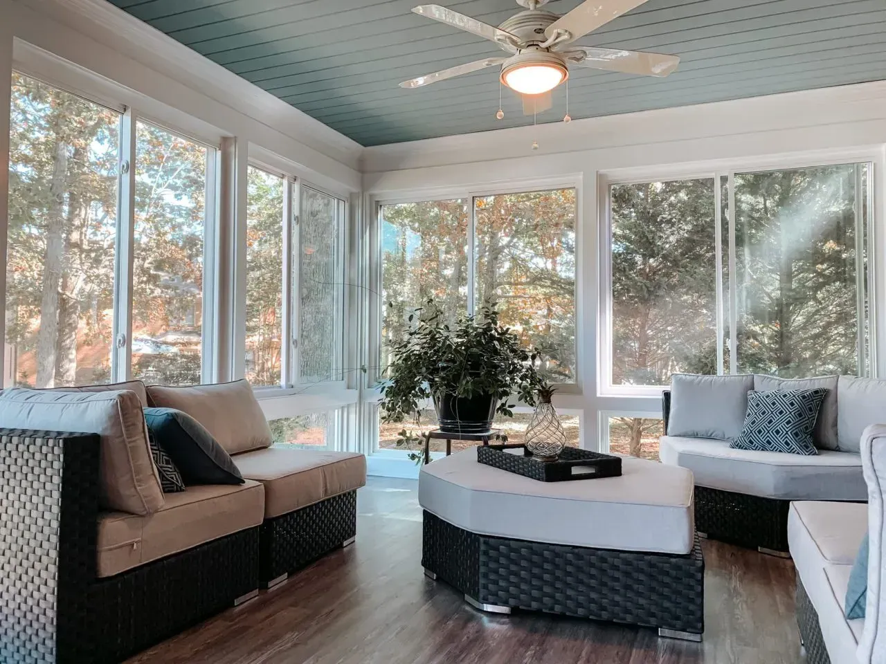 A living room with a lot of windows and a ceiling fan
