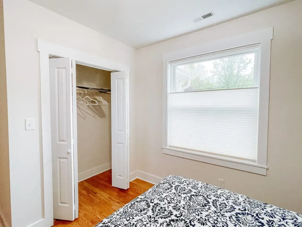 A bedroom with a bed , closet and window.