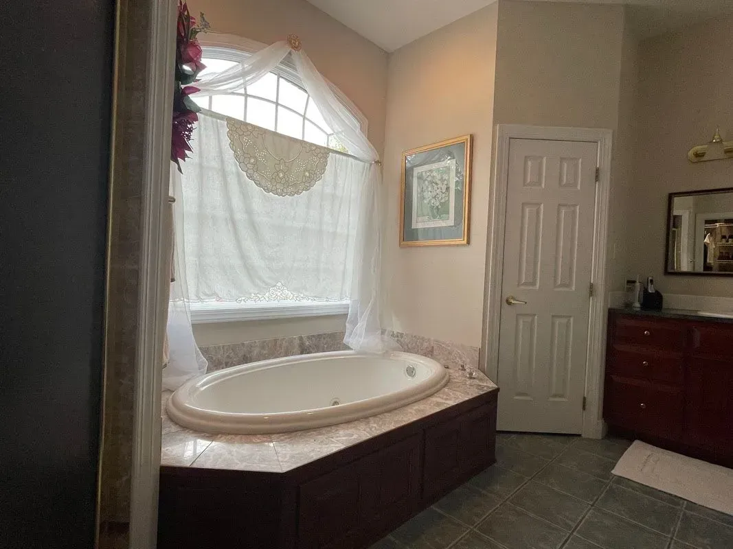 A bathroom with a jacuzzi tub and a window.