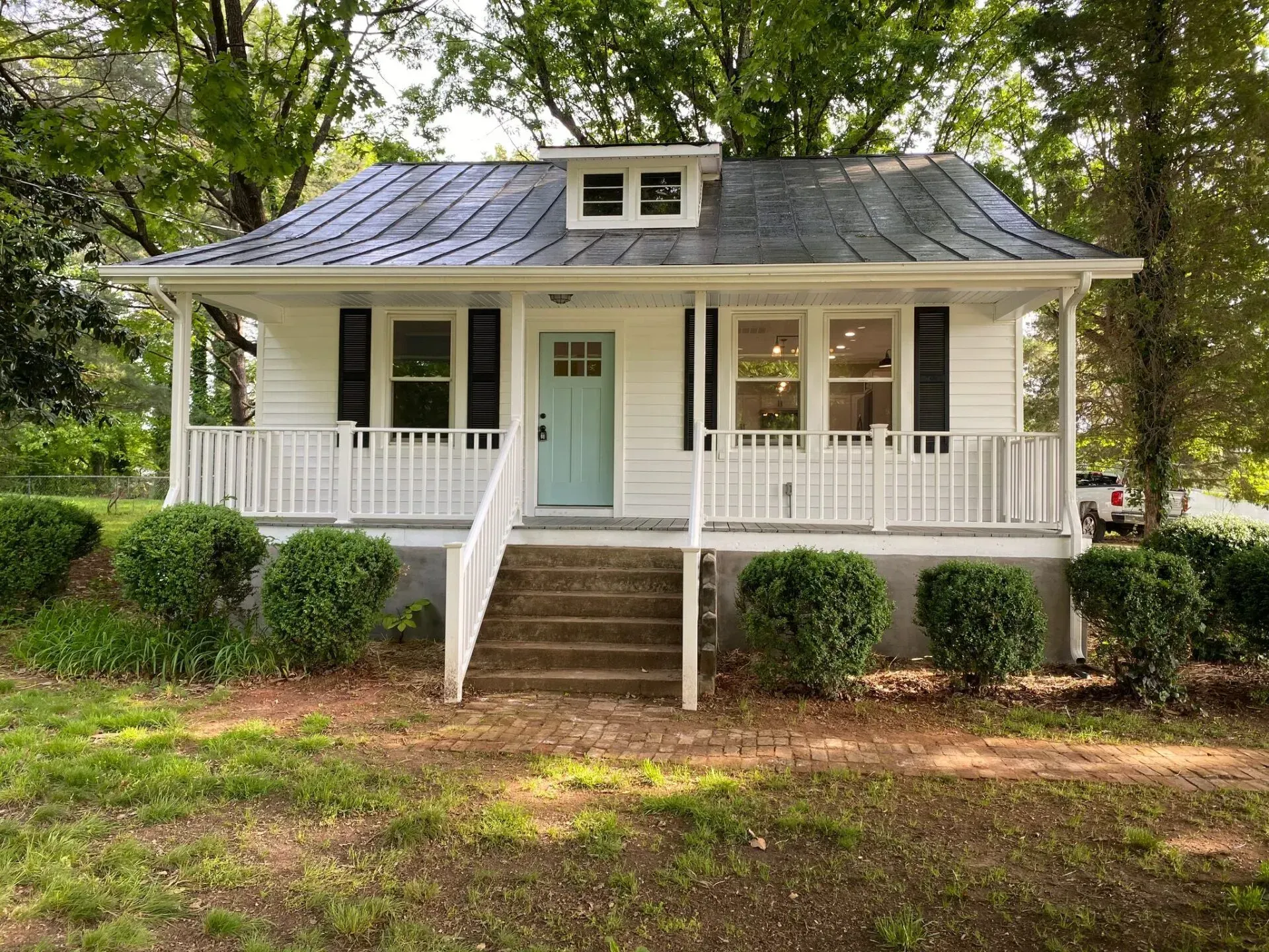 A small white house with a blue door and a porch.