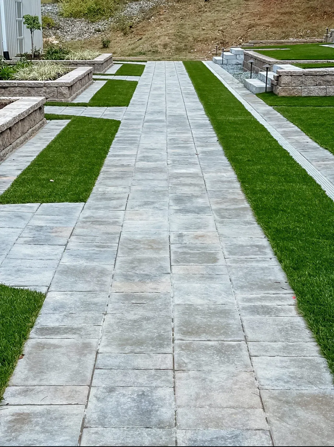 A brick walkway going through a lush green field