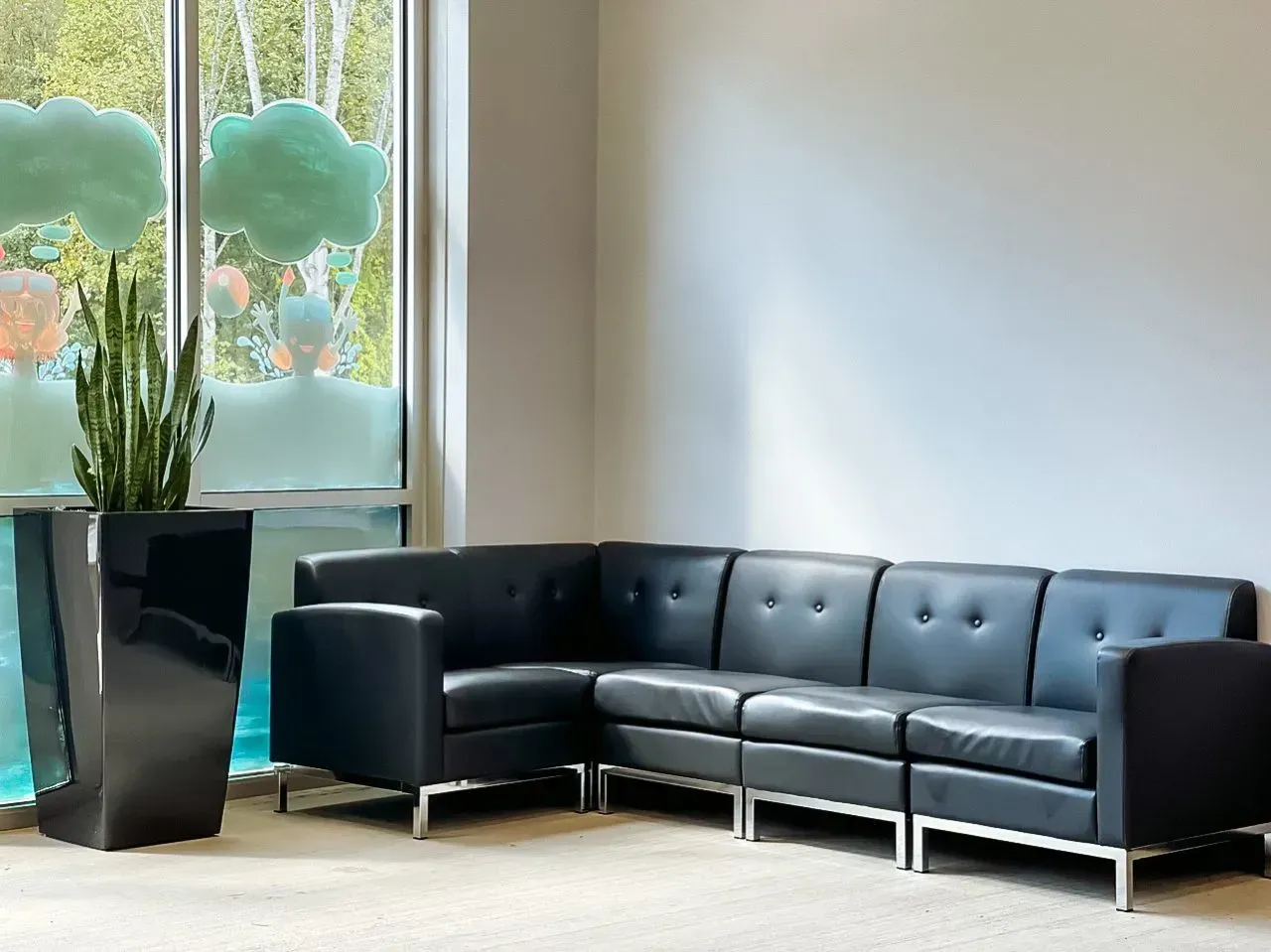 A waiting room with a couch and chairs in front of a window