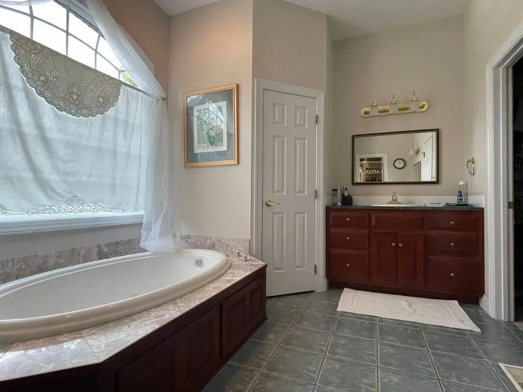 A bathroom with a tub , sink and mirror.