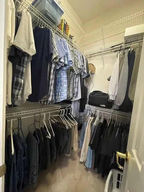 A walk in closet filled with lots of clothes and a laundry basket.