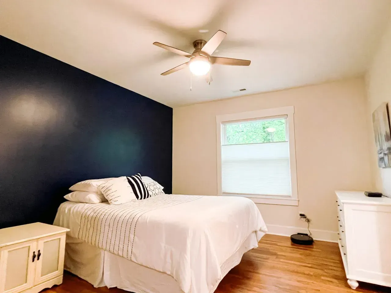 A bedroom with a bed , nightstand , dresser and ceiling fan.