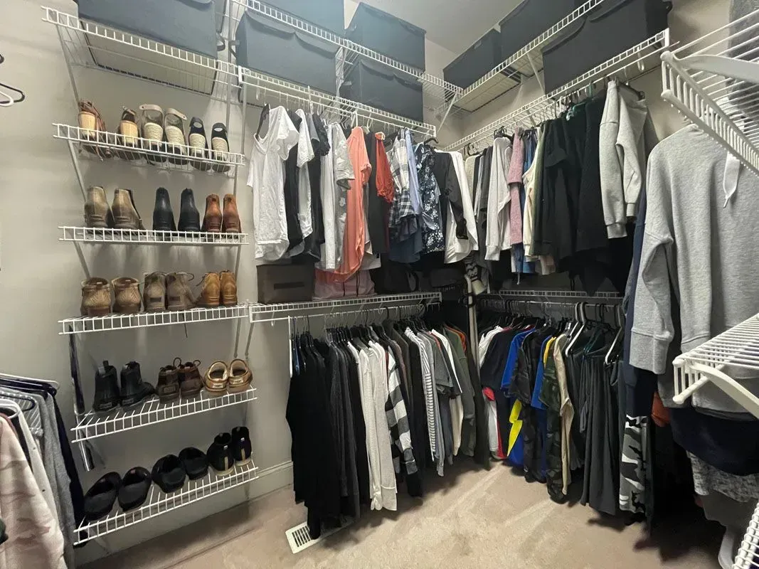 A walk in closet filled with lots of clothes and shoes.