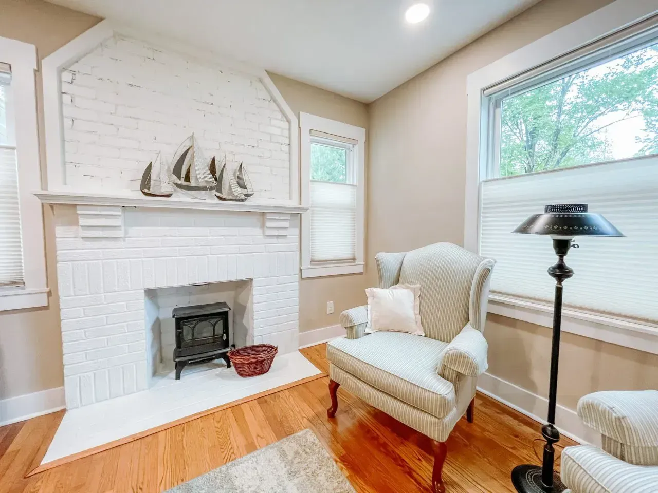 A living room with a fireplace , chair and lamp.