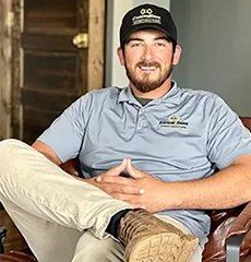 A man is sitting on a couch wearing a hat and boots.