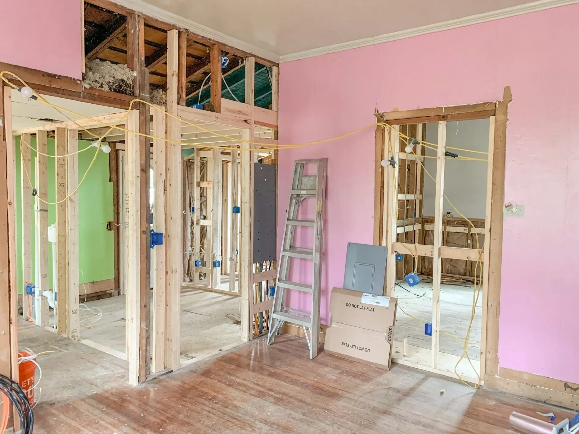 A room under construction with pink walls and a ladder.