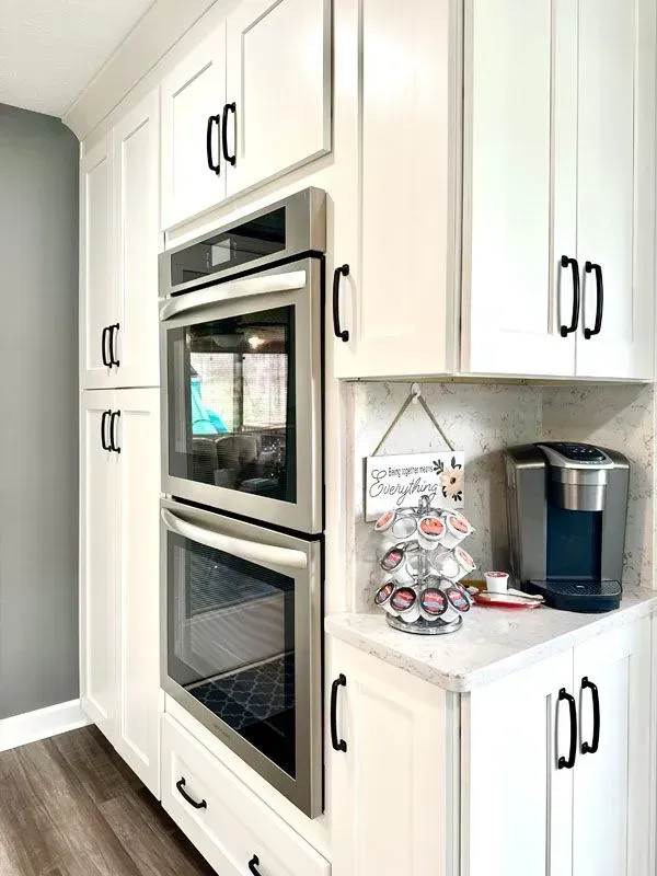 A kitchen with white cabinets , stainless steel appliances , and a coffee maker.