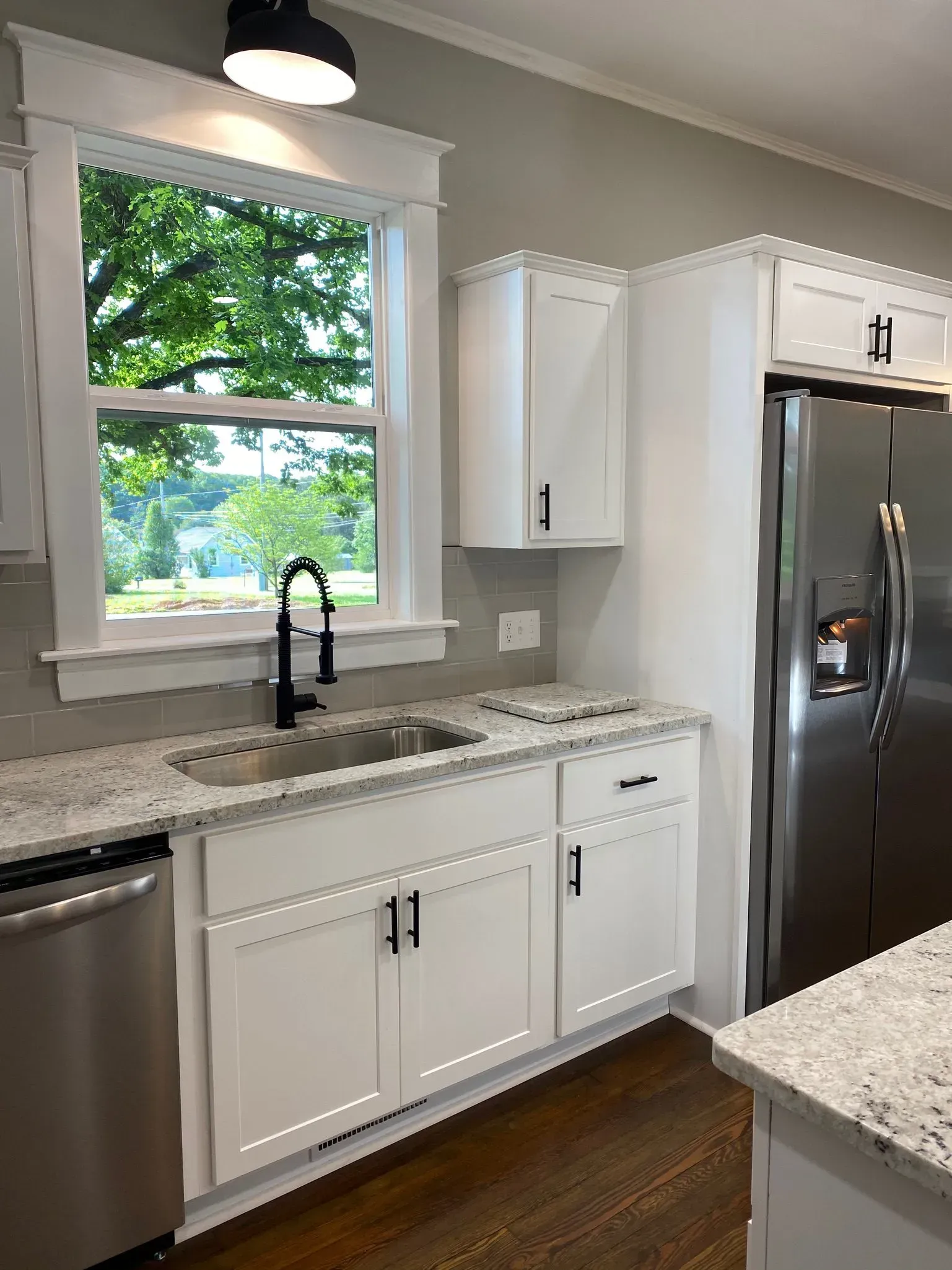 A kitchen with white cabinets , stainless steel appliances , a sink , and a refrigerator.