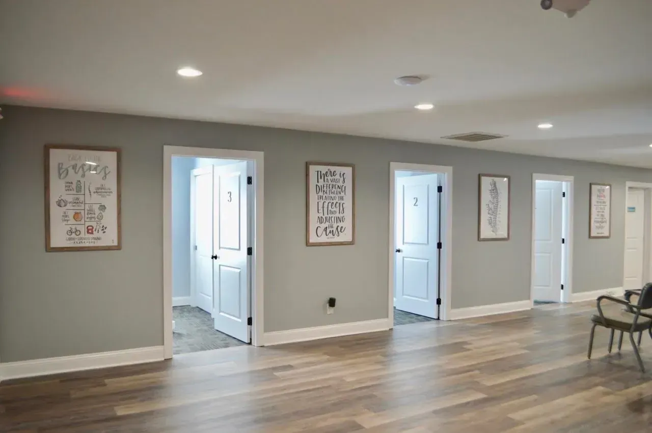 A long hallway with a lot of doors and a wooden floor.