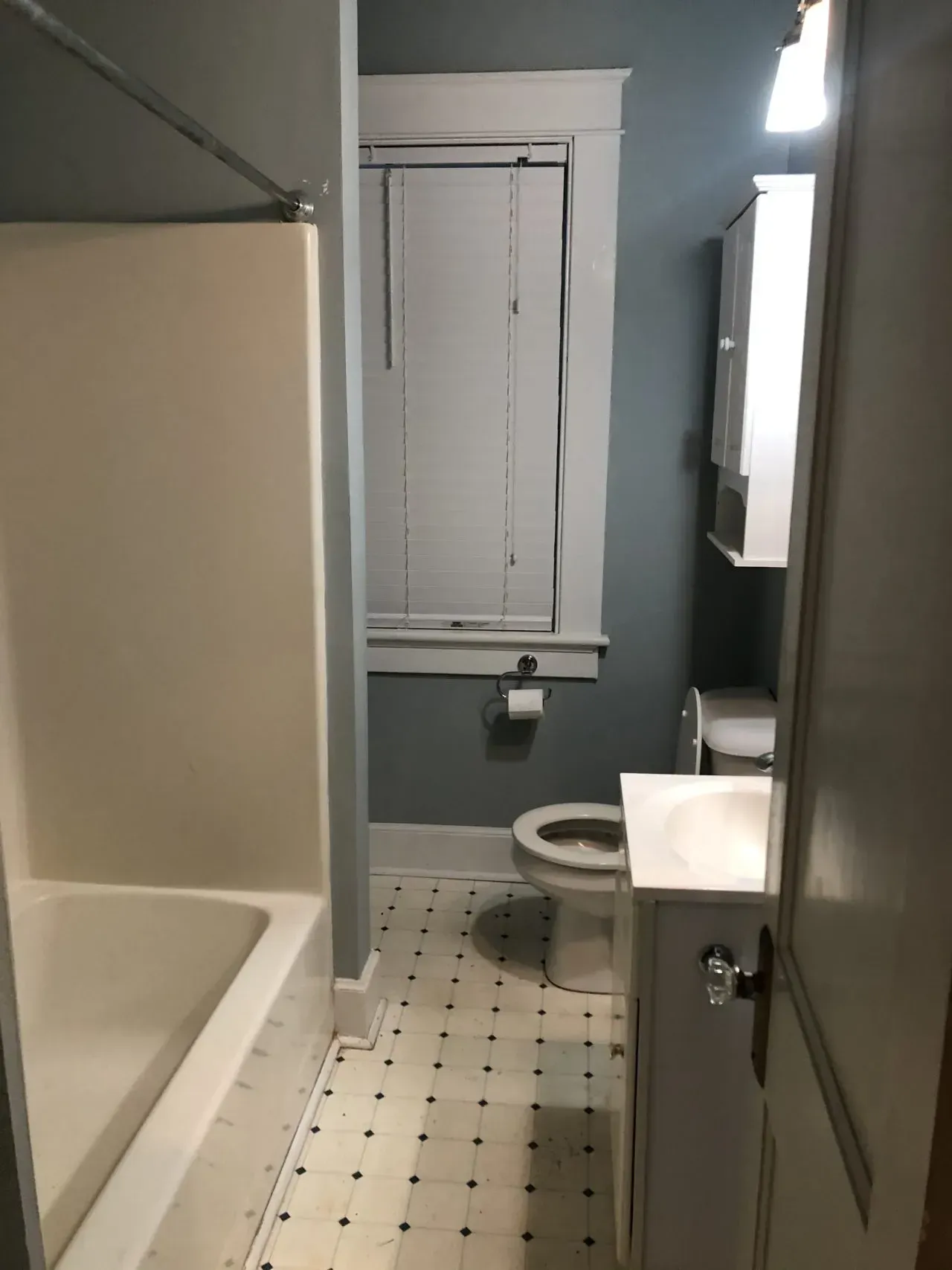 A bathroom with a toilet , sink , shower and window