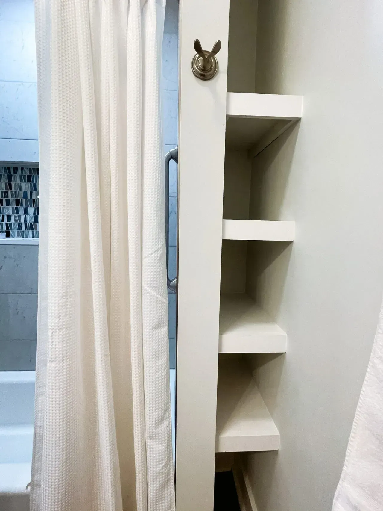 A bathroom with a shower curtain and shelves
