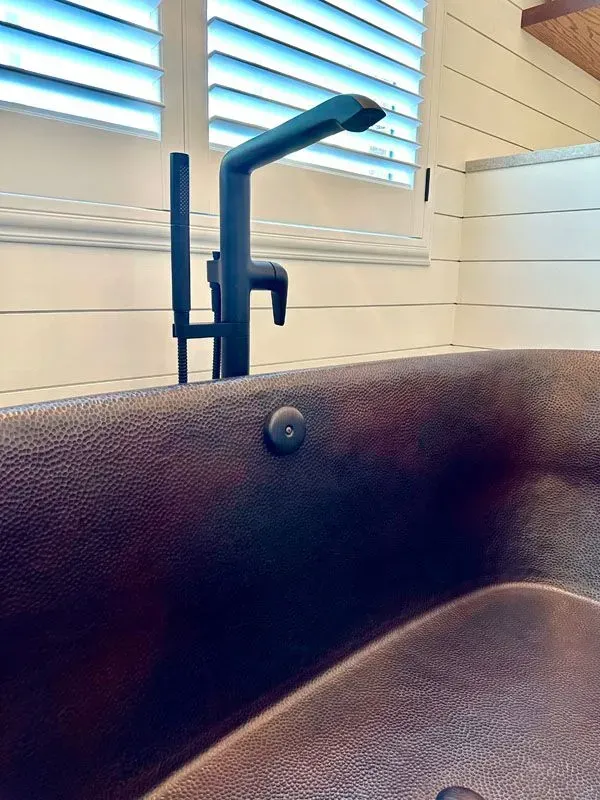 A close up of a bathtub with a black faucet in a bathroom.
