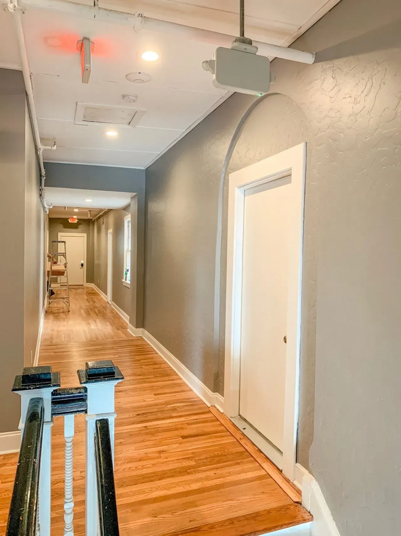 A long hallway with wooden floors and stairs in a house.