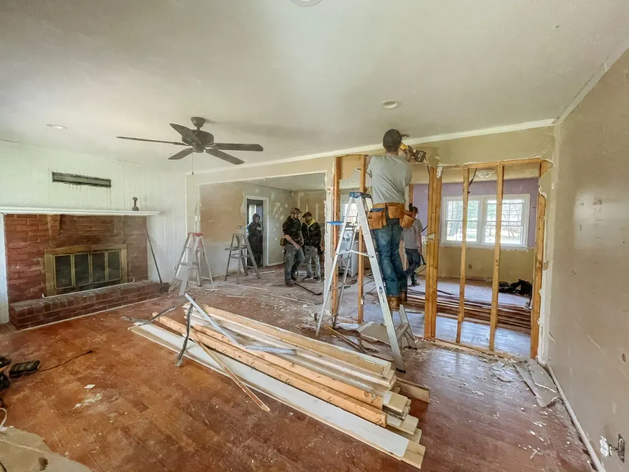 A man is standing on a ladder in a living room.
