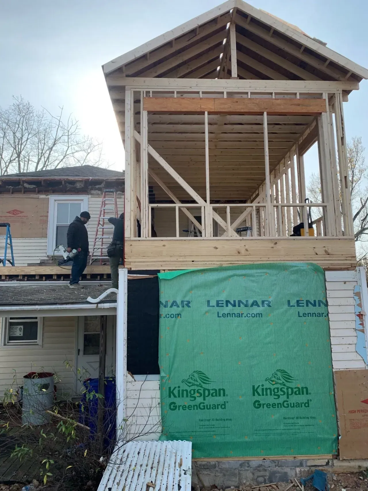 A man is standing on the roof of a house under construction.