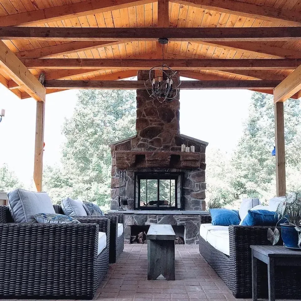 A living room with wicker furniture and a stone fireplace