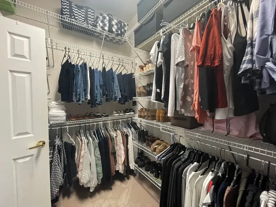 A walk in closet filled with lots of clothes and shoes.