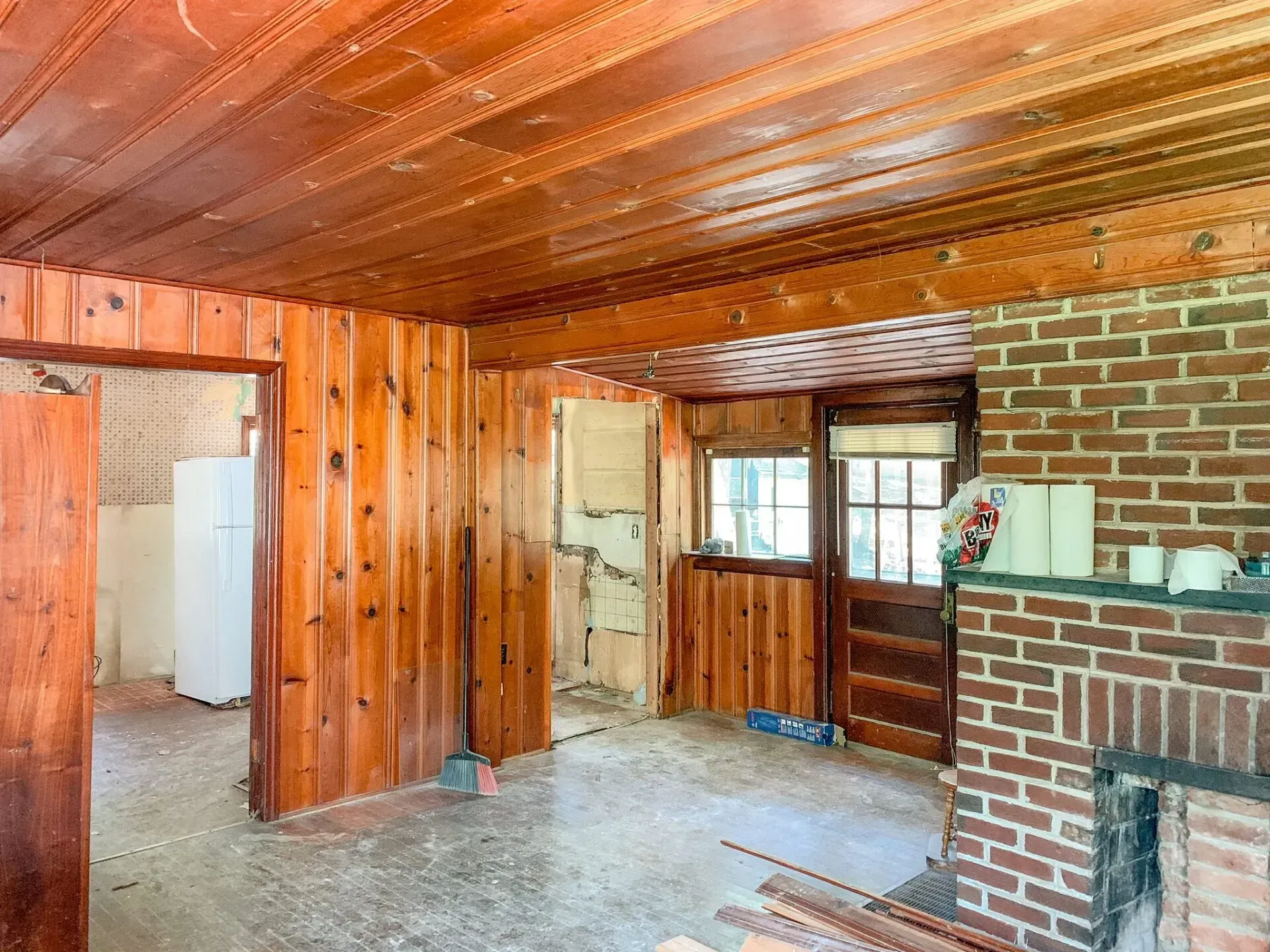 A living room with wood paneling and a brick fireplace.