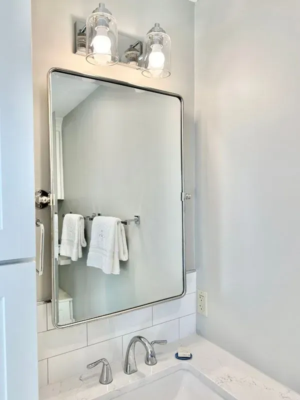 A bathroom with a sink , mirror and towel rack.
