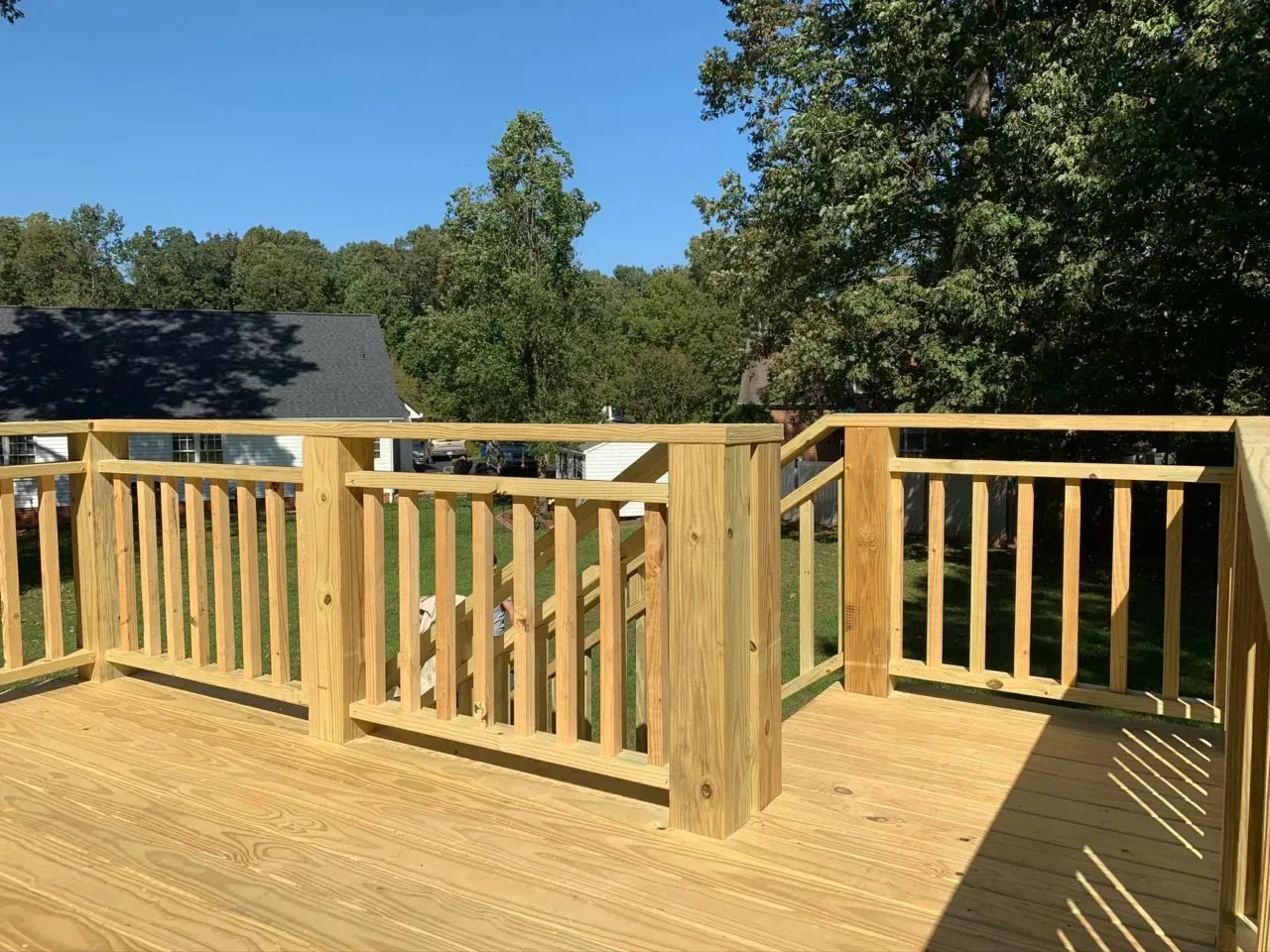 A wooden deck with a railing and trees in the background