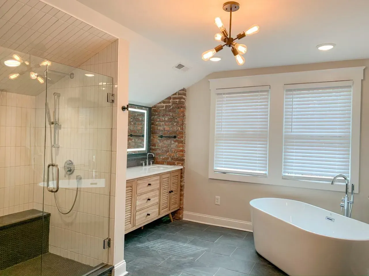 A bathroom with a tub , sink , shower and window.