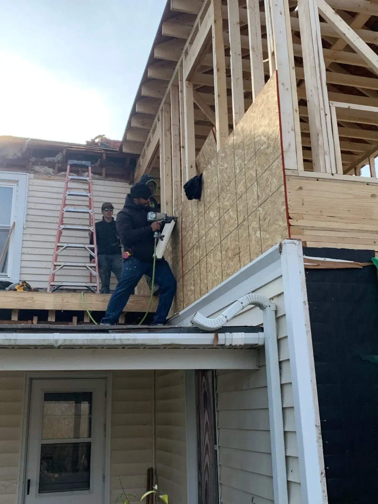 A group of men are working on the side of a house.