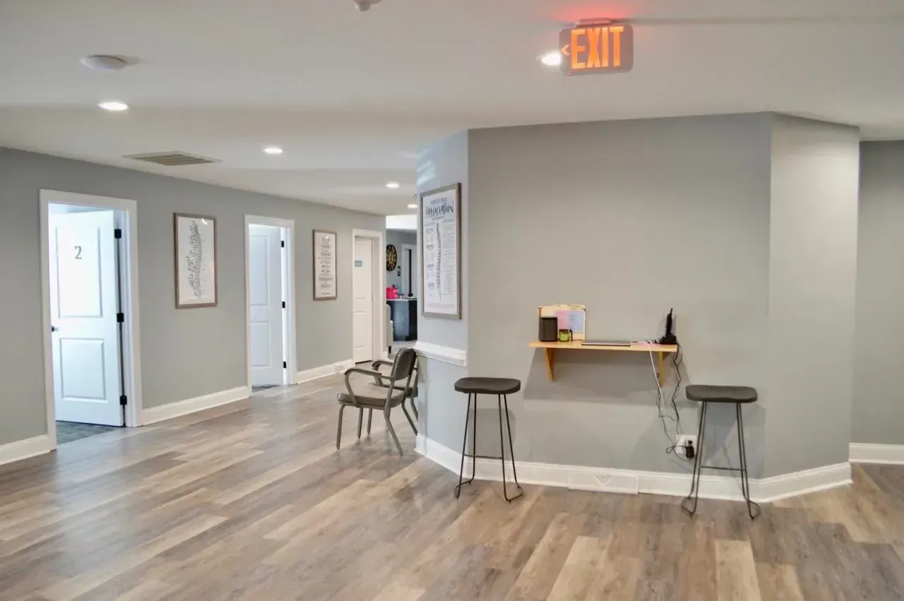 A hallway with wooden floors and a red exit sign.