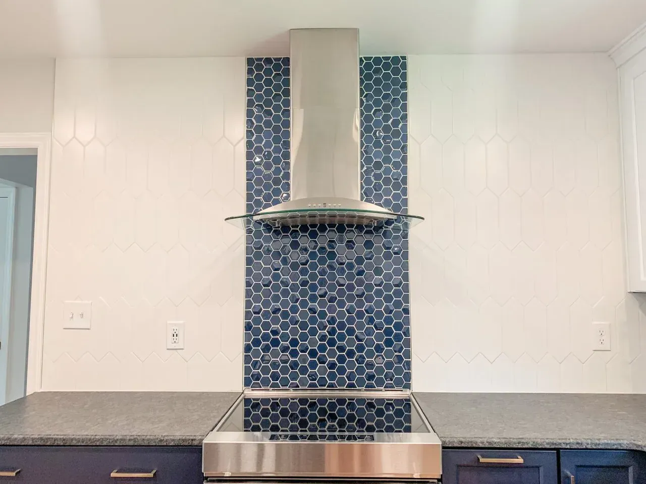 A kitchen with blue and white tiles and a stainless steel stove top oven.