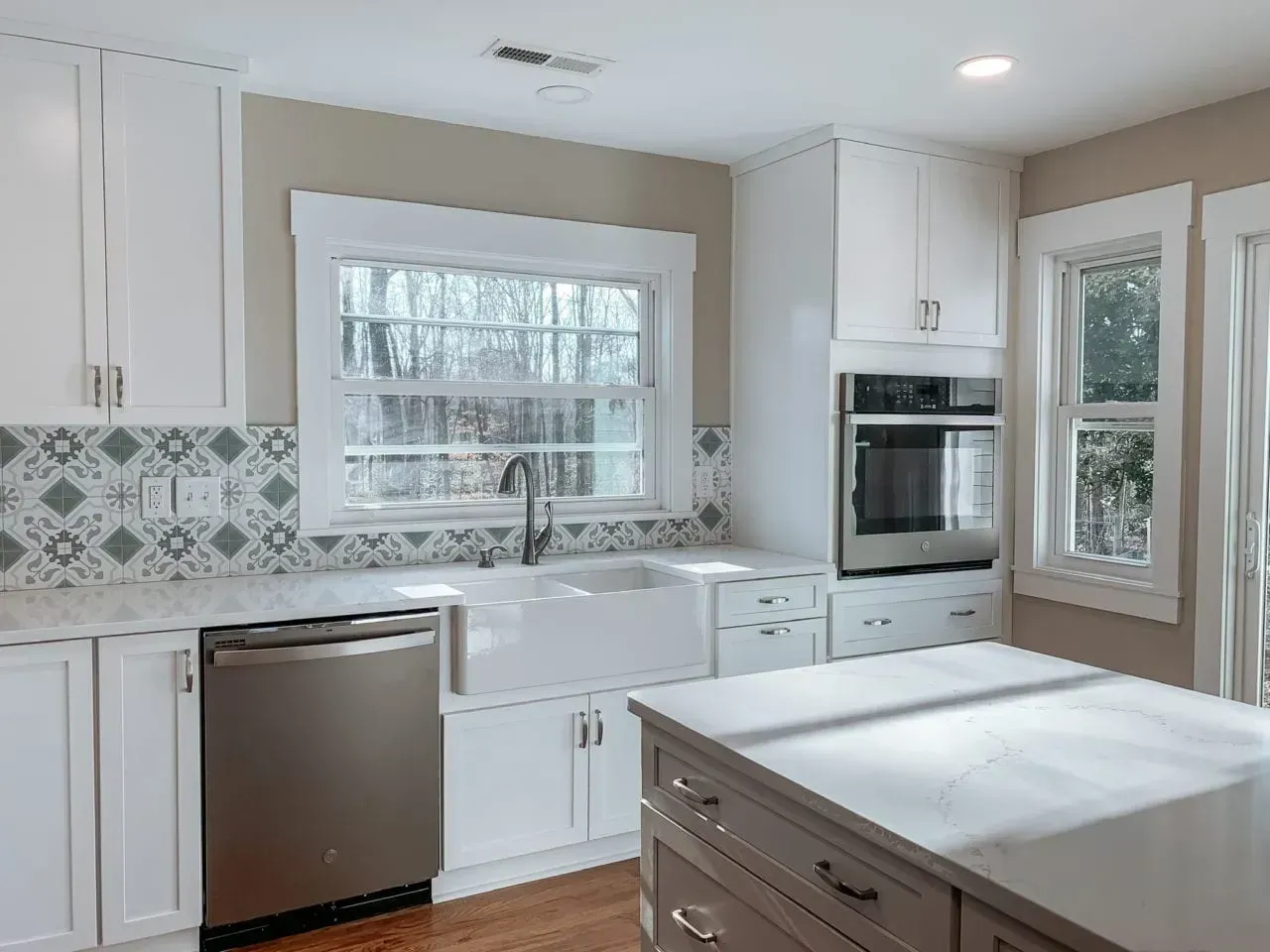 A kitchen with white cabinets , stainless steel appliances , a sink , and a large island.