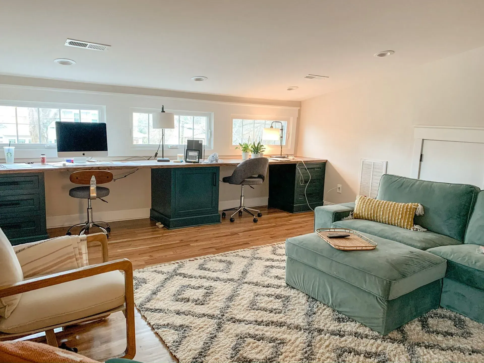 A living room with a couch , chair , desk and ottoman.