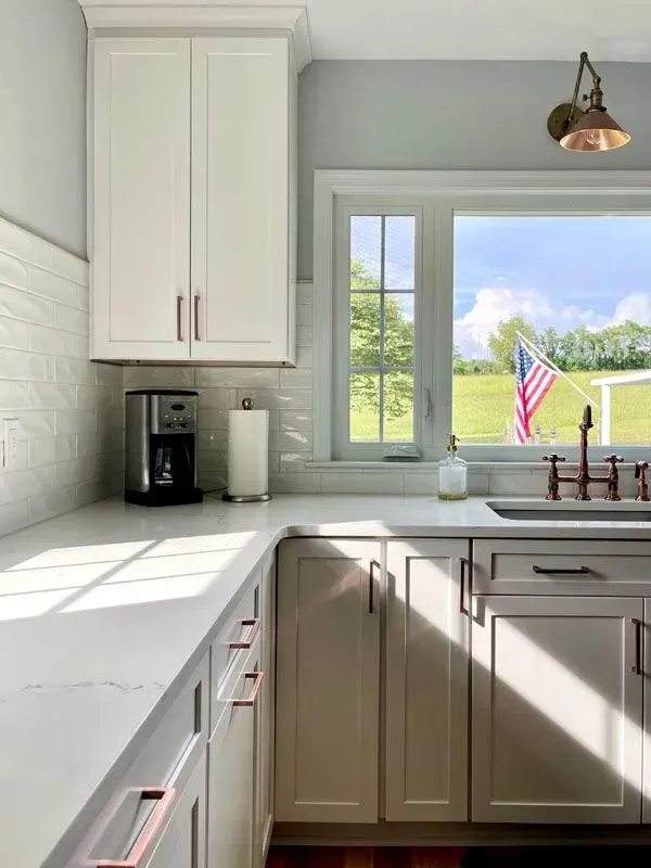 A kitchen with white cabinets a sink and a window