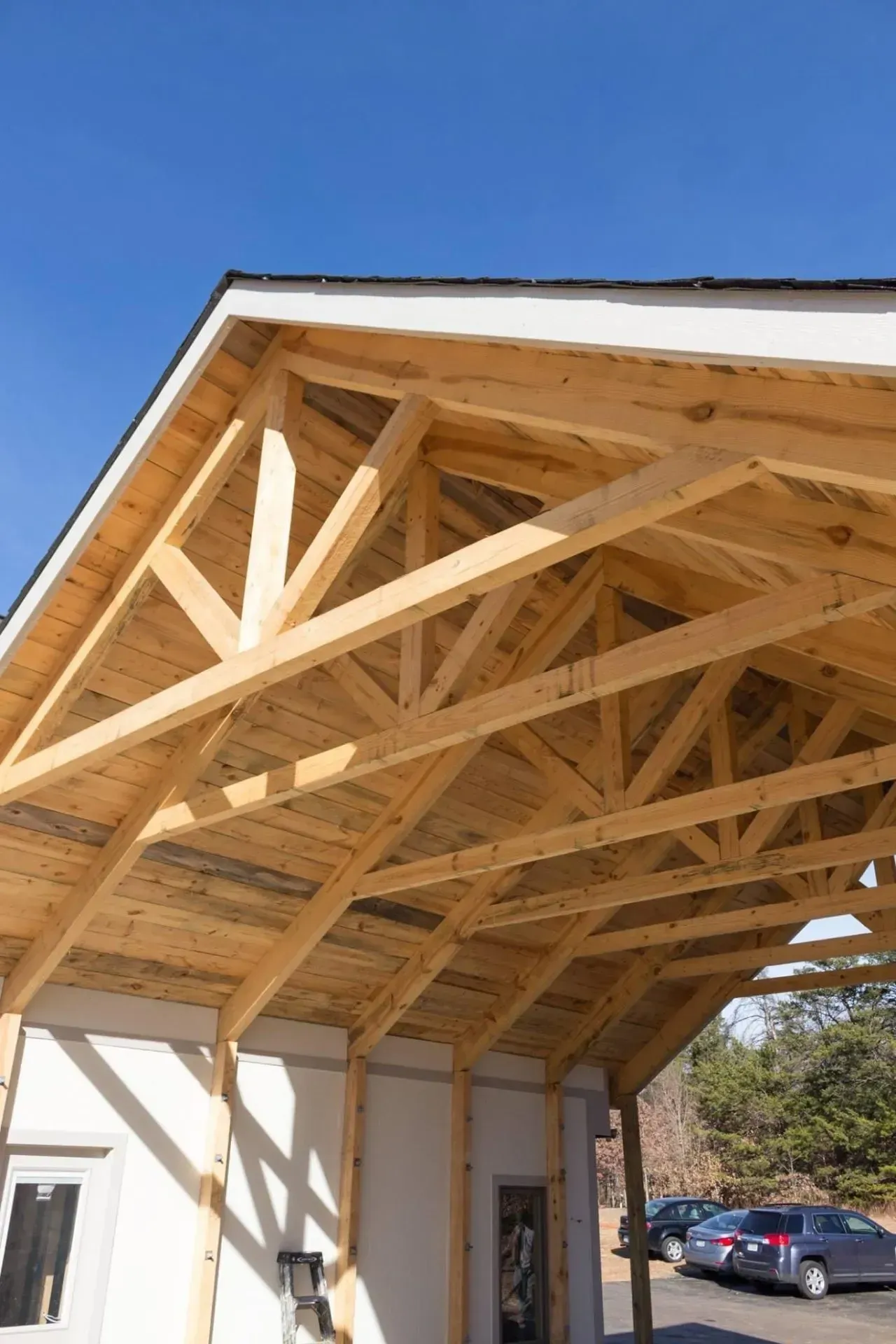 A carport with a wooden roof and a blue sky in the background.