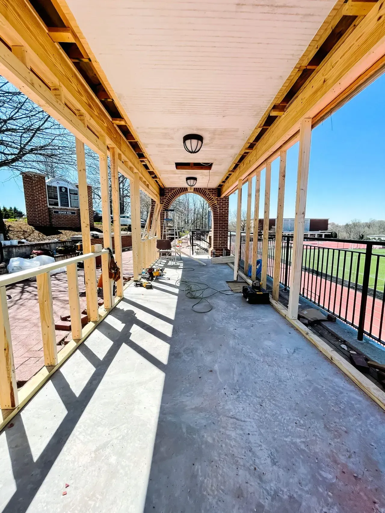 A long wooden walkway with a brick archway in the middle is under construction.