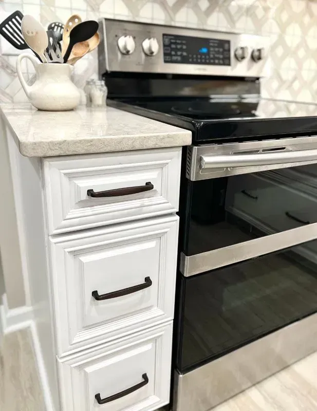 A kitchen with a black stove top oven and white cabinets.