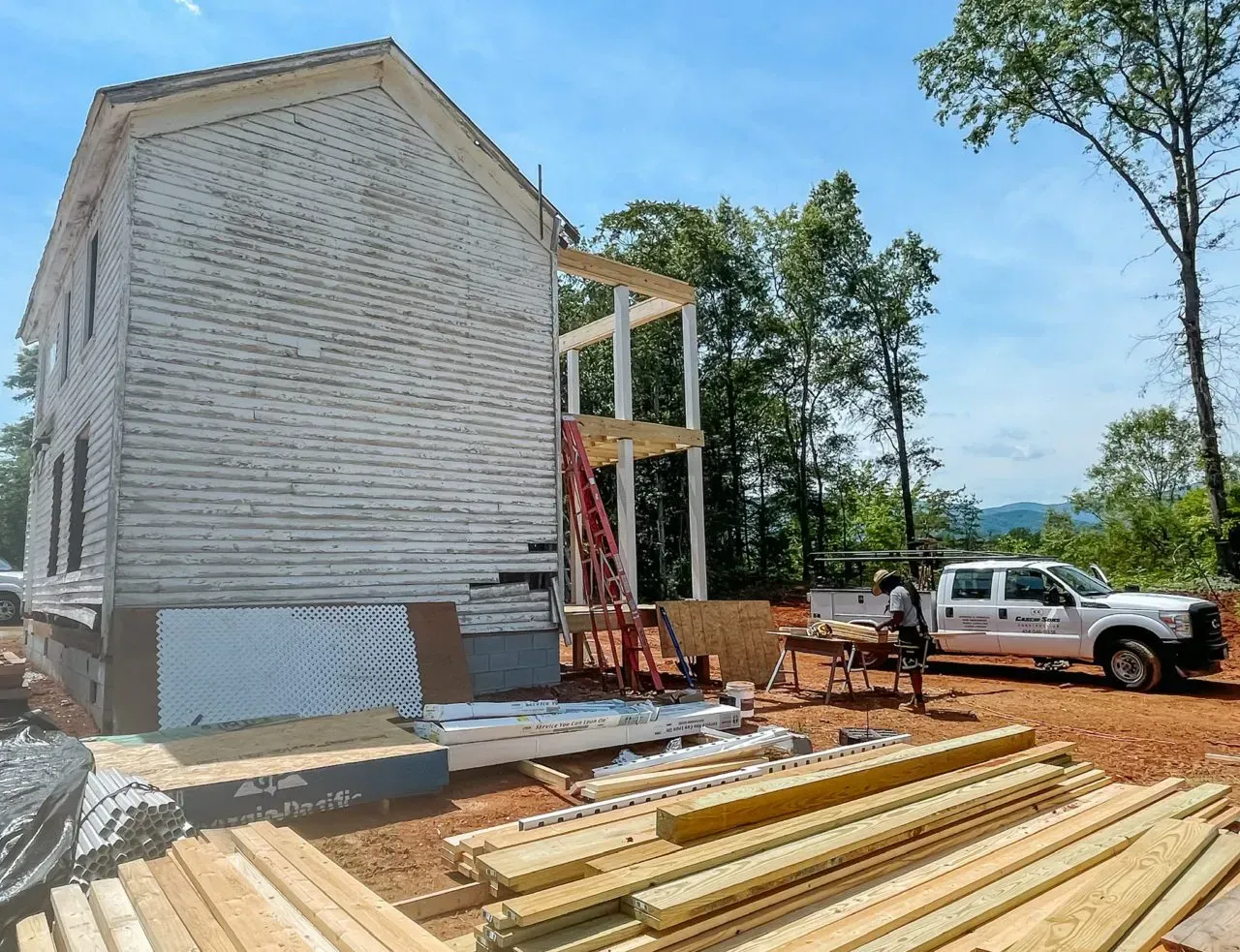 A white truck is parked in front of a house under construction.