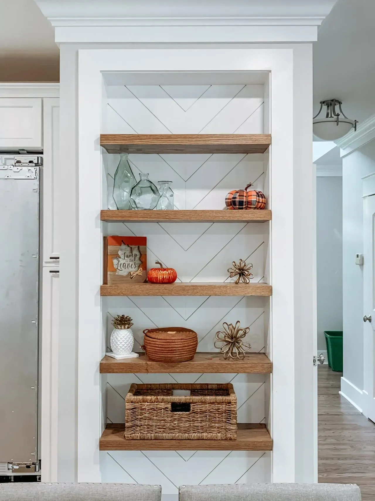 A kitchen with wooden shelves and a stainless steel refrigerator.