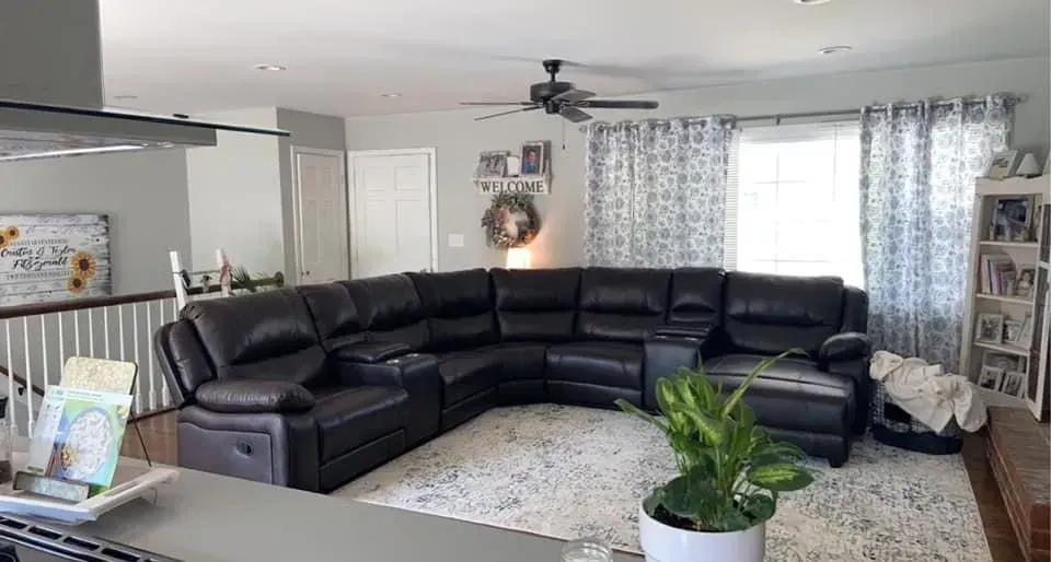 A living room with a large sectional couch and a ceiling fan.
