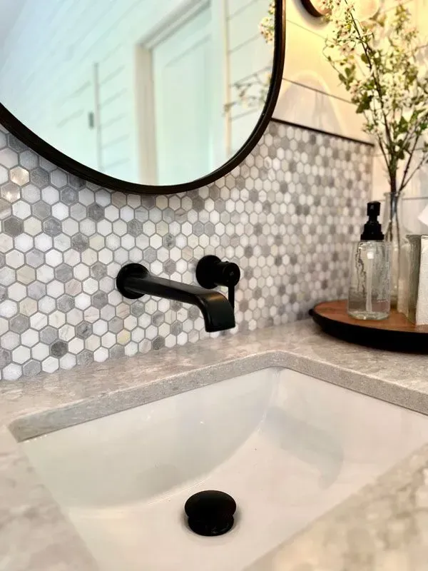 A bathroom sink with a round mirror above it.