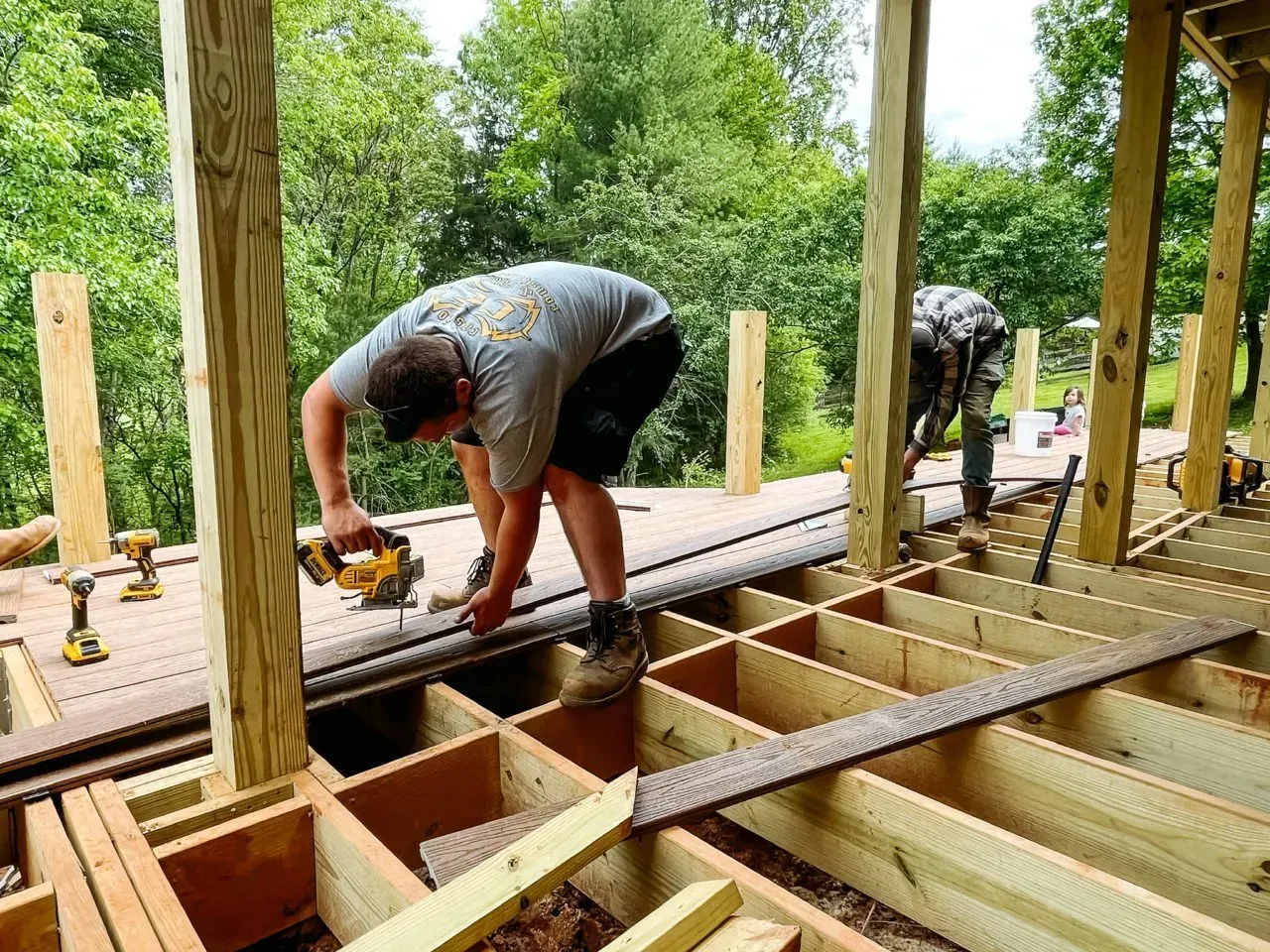 Two men are working on a wooden deck.