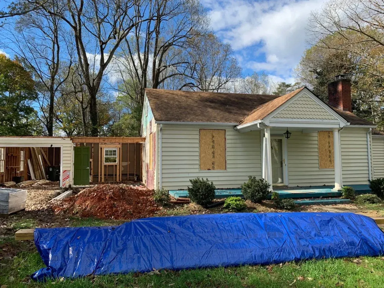 A house under construction with a blue tarp in front of it.
