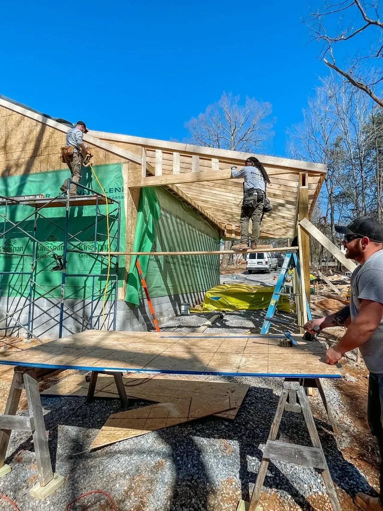 A group of construction workers are working on a house under construction.