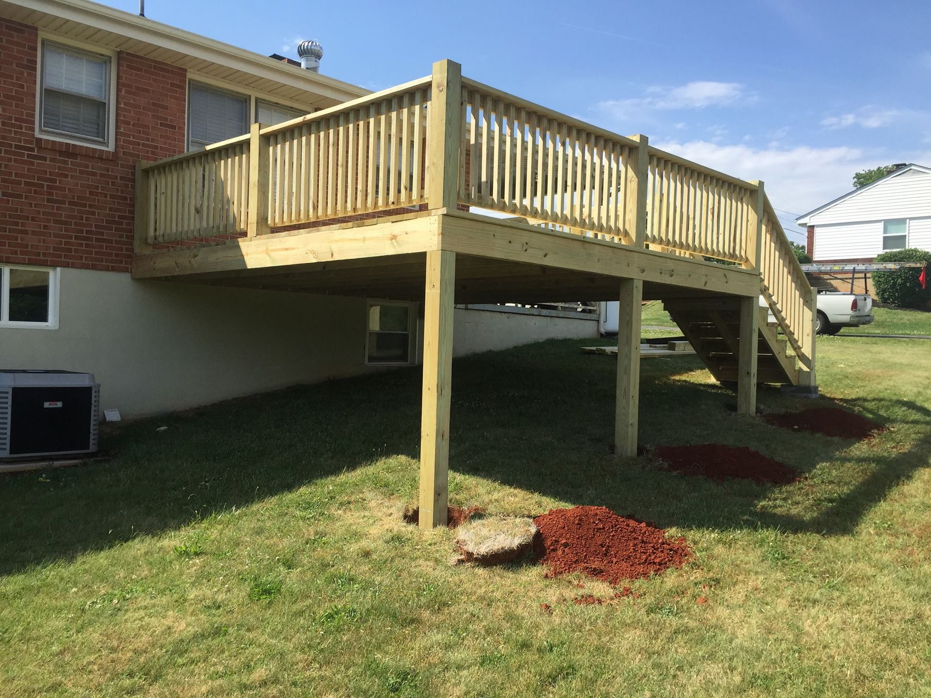 A wooden deck with stairs is in the backyard of a house.