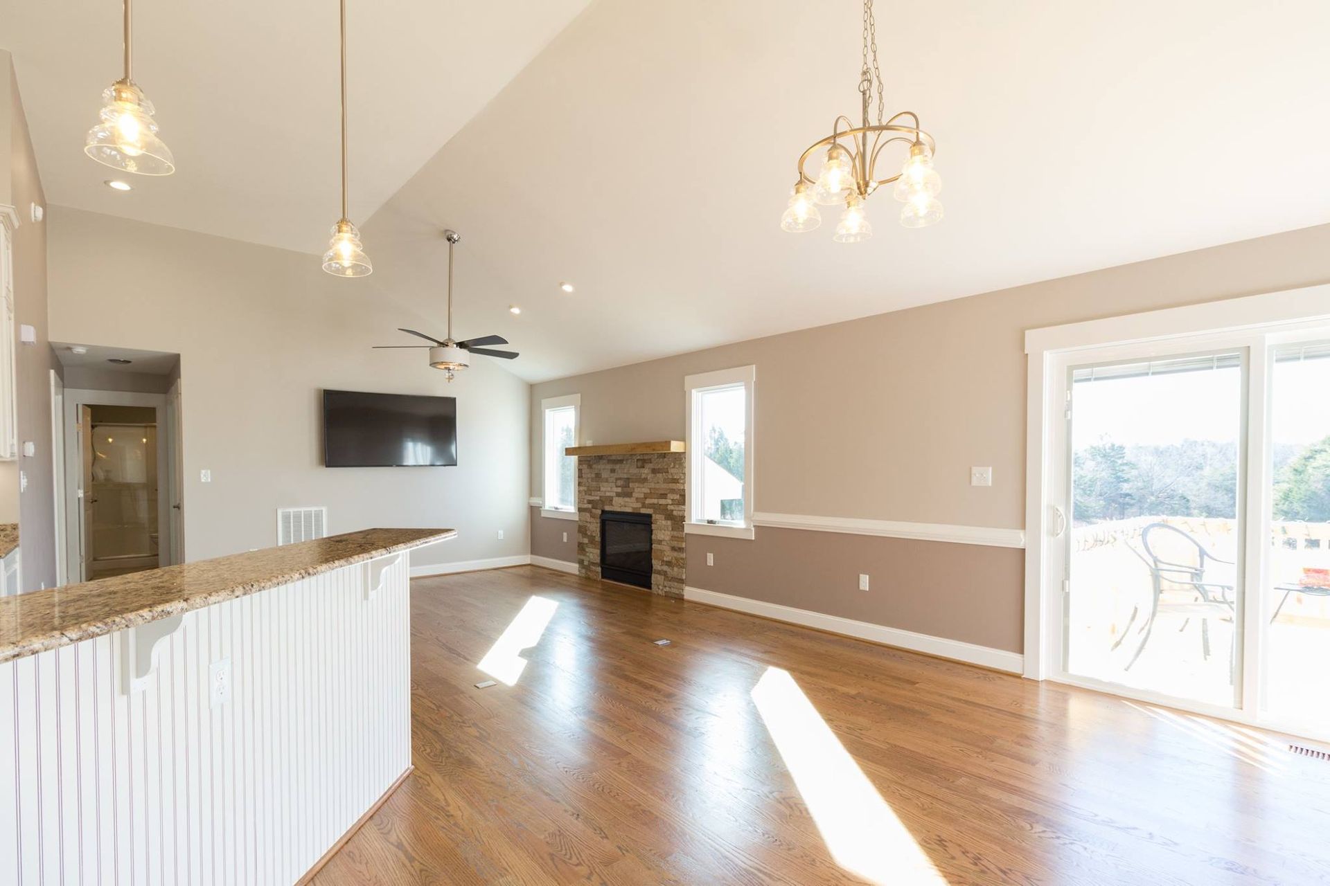 An empty living room with hardwood floors , a fireplace and a flat screen tv.